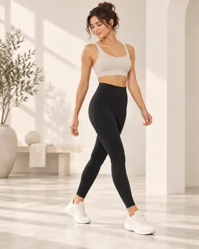 Woman walking in black high-waisted leggings in a bright minimalist studio